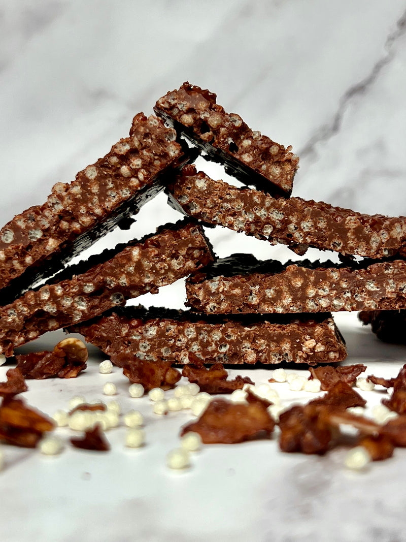 Stacked chocolate bark bars made with LIFTER Crispies on a marble surface