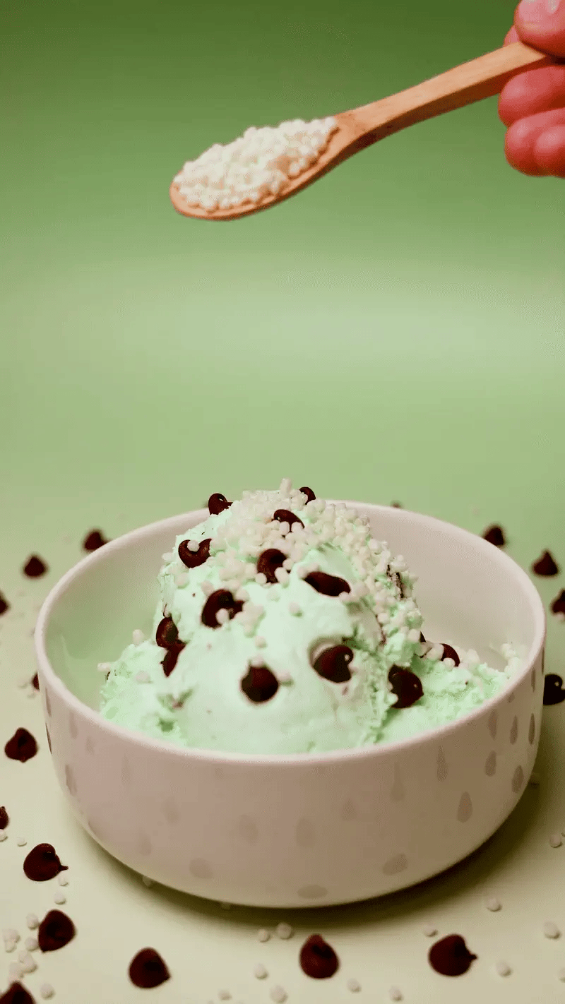 LIFTER Crispies being spooned onto a scoop of mint chocolate chip ice cream